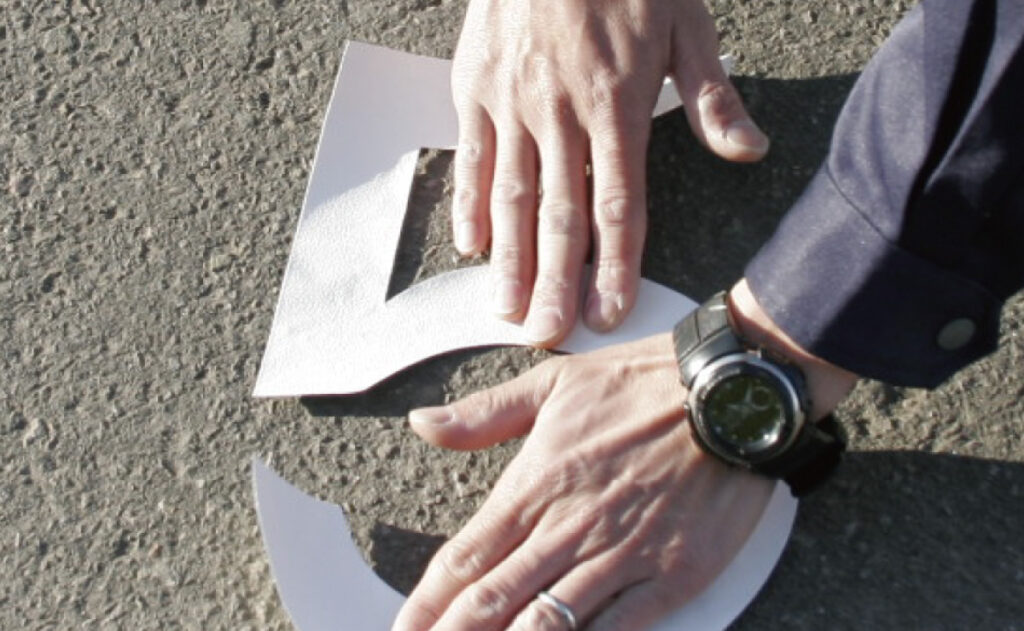 コンクリート・アスファルトに貼れるステッカーを貼り付けする様子